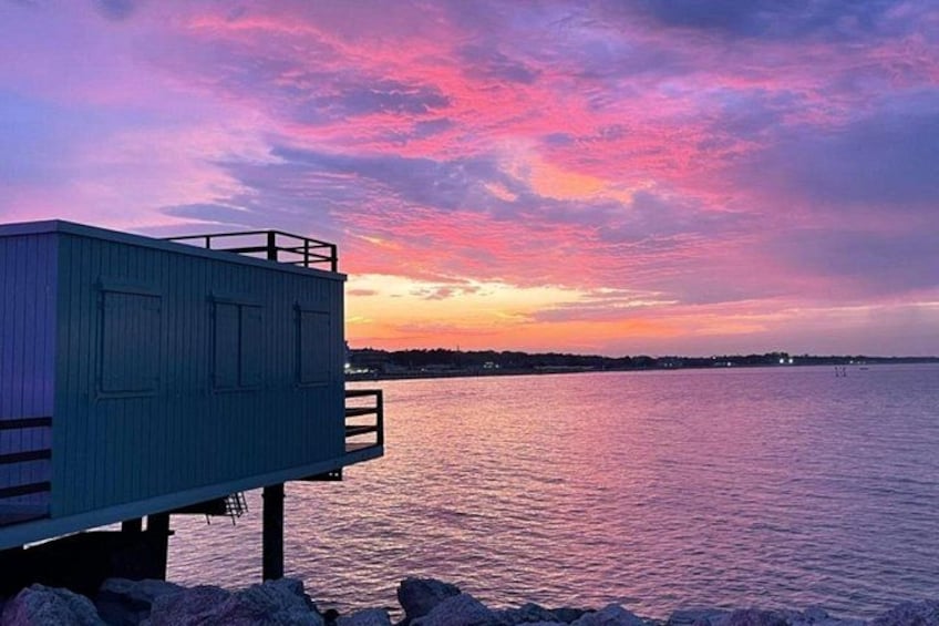 A dock extending into a body of water with a sunset in the background. 5