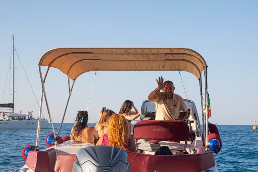Un bateau doté d’un auvent, avec des passagers à bord, et un voilier en arrière-plan. 2
