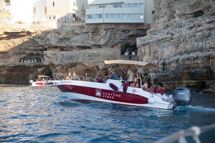 Un bateau nommé « Venture Vibes » transportant des passagers, naviguant près de falaises rocheuses et de bâtiments. 4