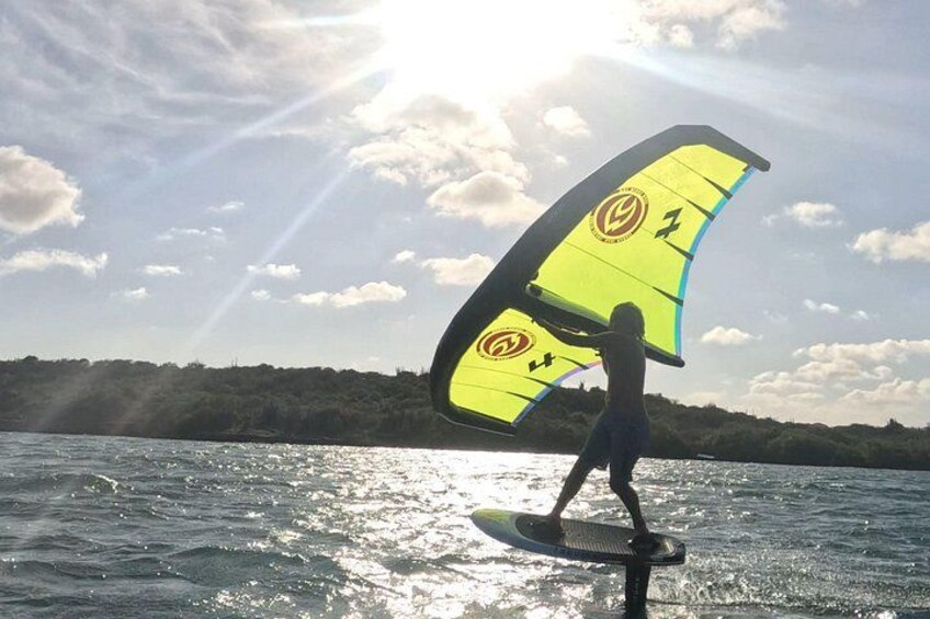 A person windsurfing on a body of water with a bright sun in the background. 2