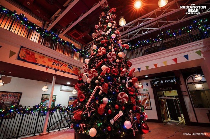 Un gran árbol de Navidad decorado en un centro comercial, con un cartel de 'Lost & Found' al fondo. 2