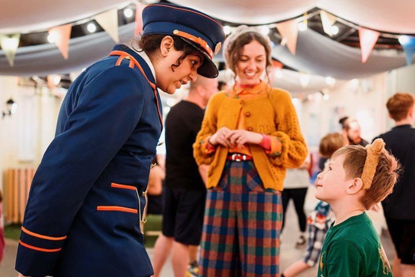 A person in a uniform interacting with a child and an adult in a festive indoor setting. 2