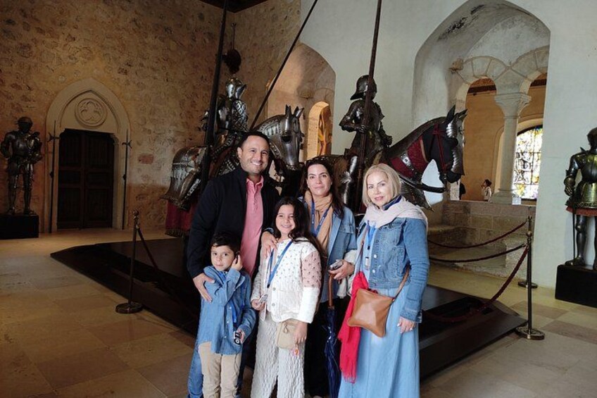 Una familia posando frente a una exhibición histórica con armaduras y esculturas. 4