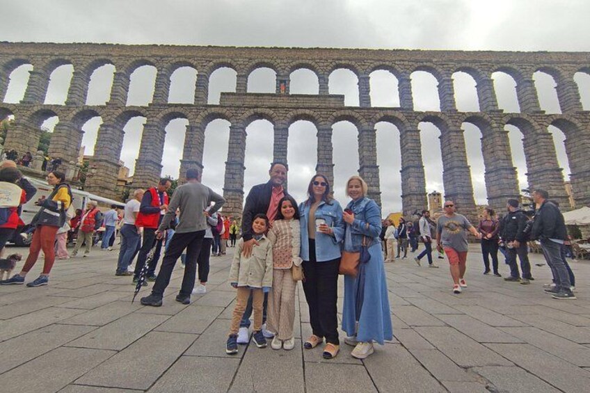 Una familia posando frente a un antiguo acueducto con arcos de piedra. 1