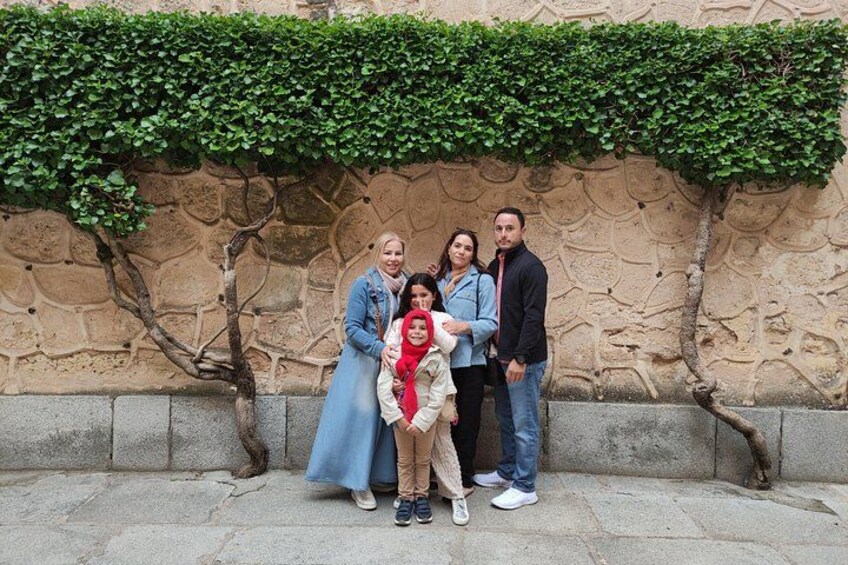 Una familia de cuatro personas frente a un muro de piedra con hiedra verde. 3
