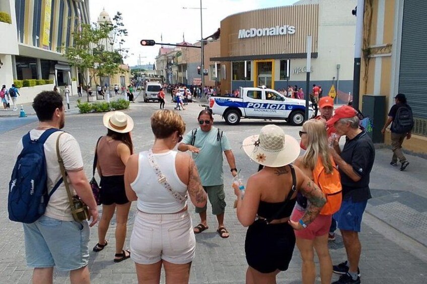 A group of people standing on a sidewalk, a police vehicle, and a McDonald's restaurant. 3