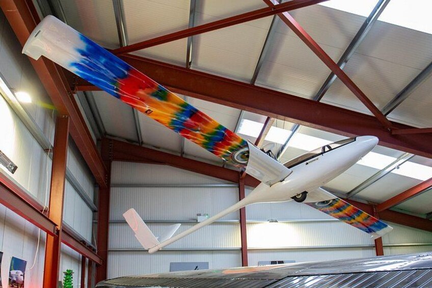 Un hangar abritant un avion blanc et des banderoles aux couleurs vives. 5