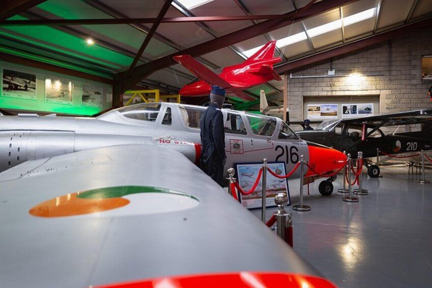 Un musée où sont exposés des avions anciens, dont un appareil rouge et blanc portant le numéro 216. 3