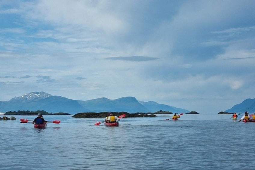 Kayakers on a calm lake with mountains in the background. 2