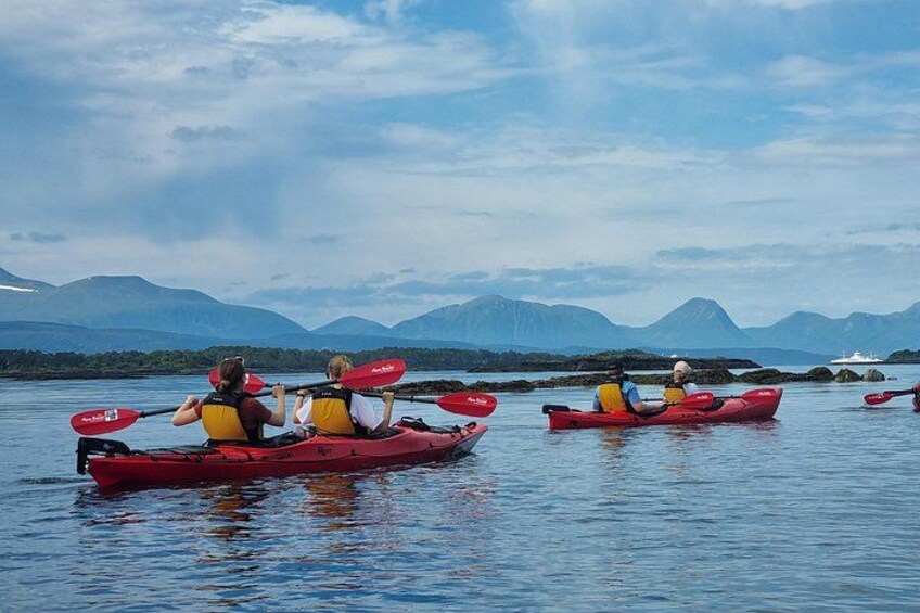 Two people kayaking on calm water with mountains in the background. 5