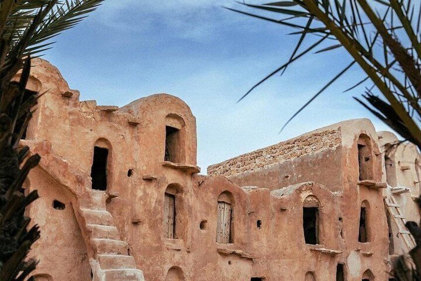 Un edificio antiguo y desgastado con ventanas de arco y una escalera. 3