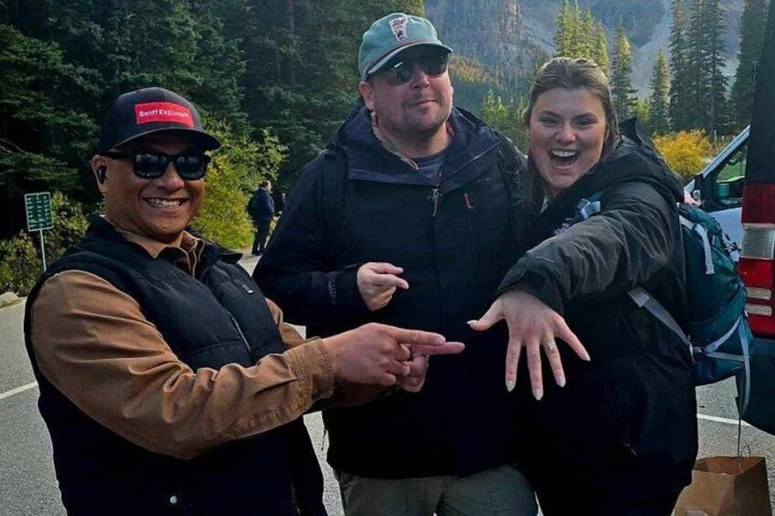 Three people standing by a road with a vehicle in the background. 4