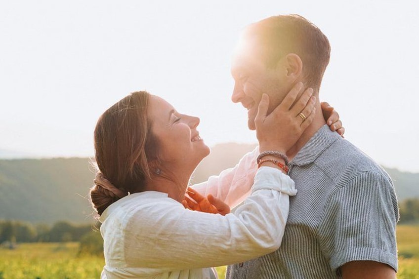 A couple embracing in a field with a mountainous background. 1