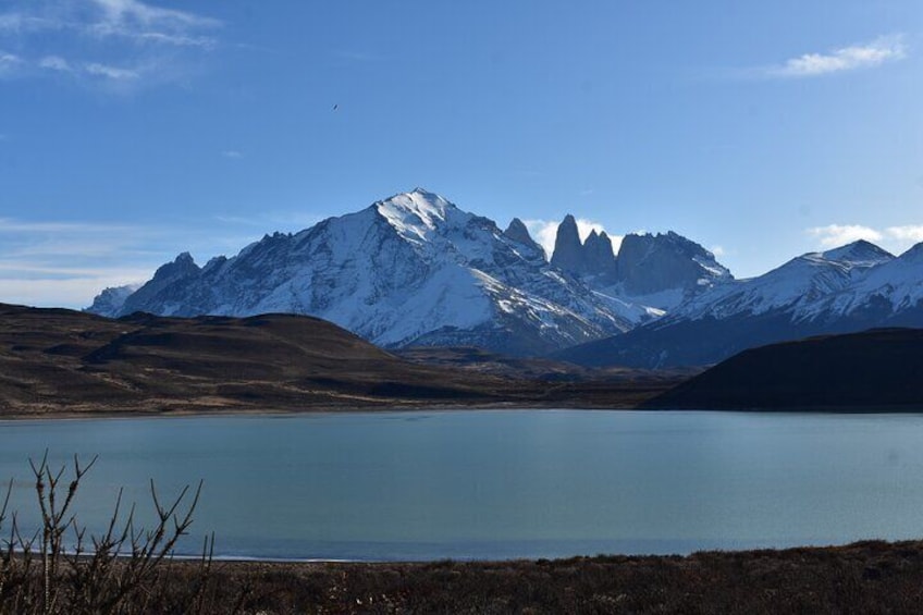 A mountain range with snow-capped peaks, a calm lake, and a clear sky. 3