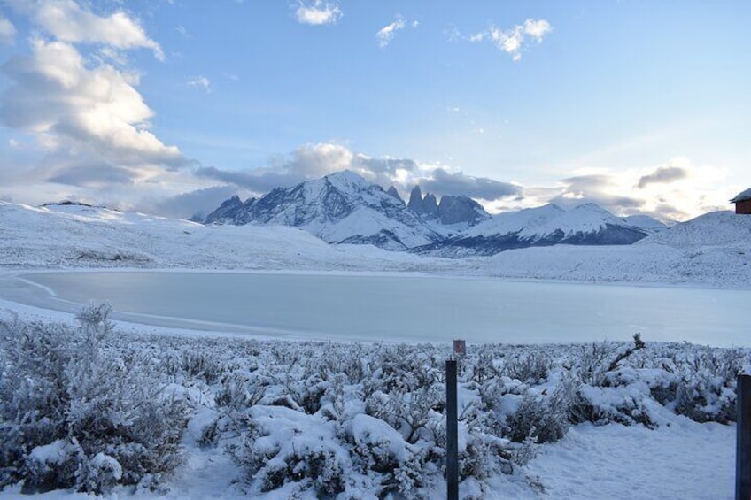 A snow-covered landscape with a frozen lake, snow-covered trees, and mountains in the background. 2