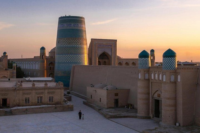 Un edificio histórico con una gran torre cilíndrica, una mezquita con un minarete y un patio empedrado. 3