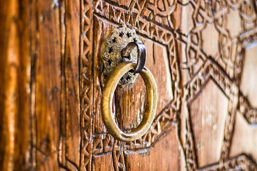 Puerta de madera con tallas intrincadas y un llamador de latón. 2