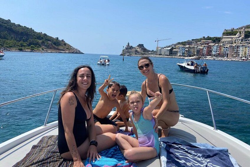 Un bote con gente en un día soleado, agua y una costa lejana con edificios. 5