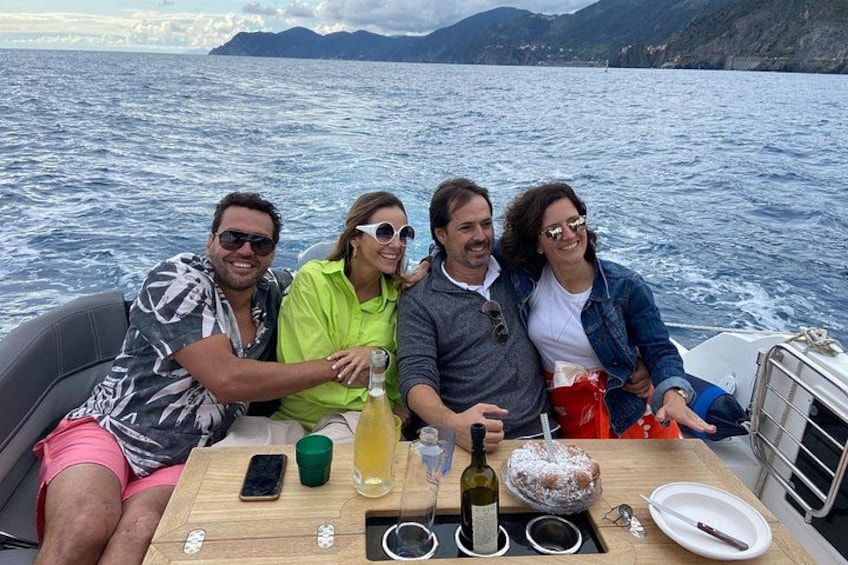 Cuatro personas en un bote, con una mesa de madera frente a ellas, sosteniendo bebidas y una botella de vino. 4
