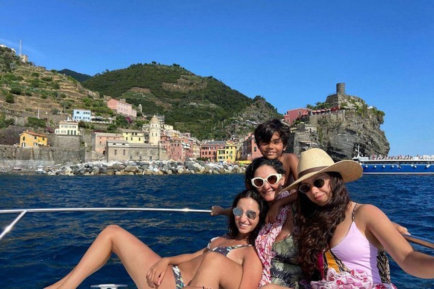 Un grupo de personas en un barco, con un pueblo costero y una colina rocosa al fondo. 2