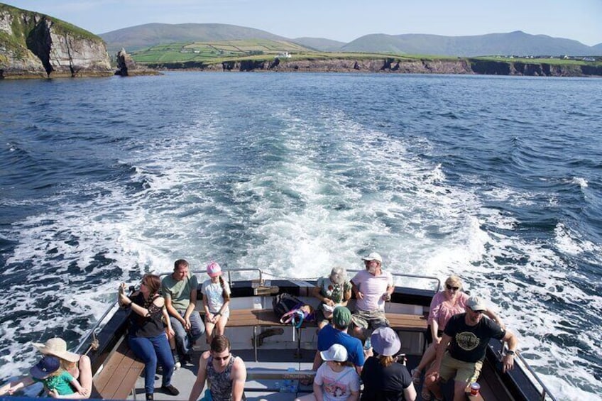 Un groupe de personnes se trouve sur un bateau, naviguant sur une étendue d’eau, avec des falaises en arrière-plan. 1