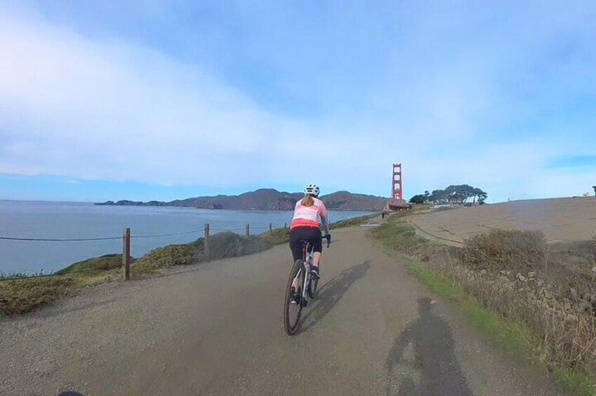En cyklist på en asfalteret sti med udsigt til Golden Gate Bridge og havet. 1