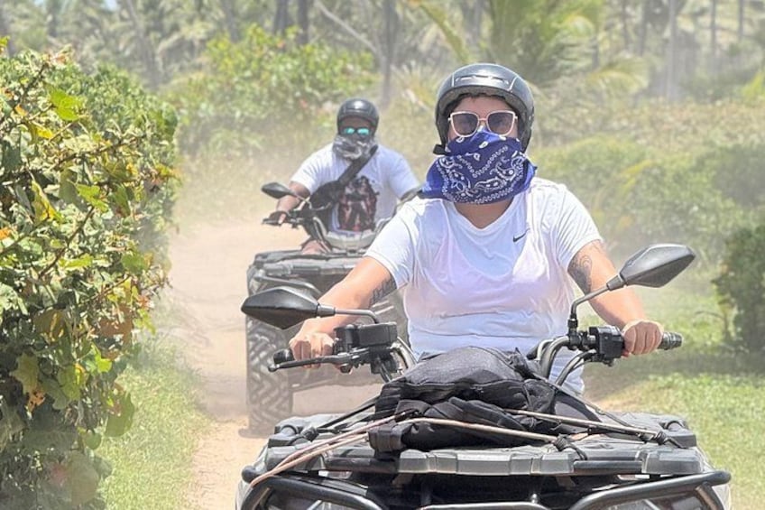 Dos personas manejando cuatrimotos por un sendero de tierra rodeado de vegetación. 5