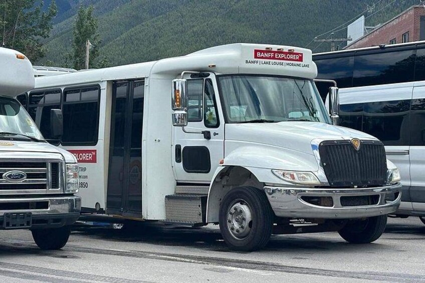 A white bus with a sign reading 'BANFF EXPLORER' parked on a road. 3