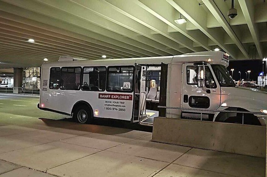 A white bus with 'BANFF EXPLORER' branding parked at a bus terminal. 2
