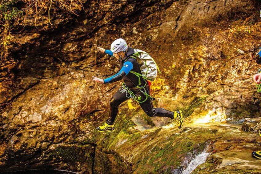 A person rappelling down a rocky cliff with a backpack and harness. 2