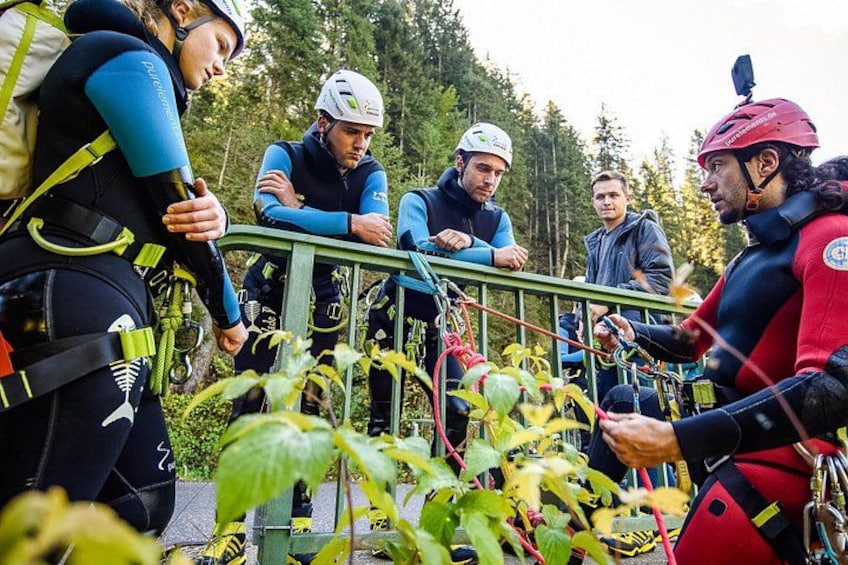 People in helmets and harnesses near a metal railing, possibly preparing for an activity. 4