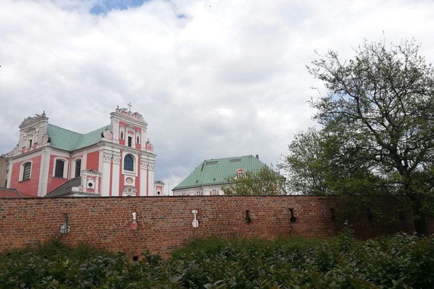 A historic church with a red brick wall and a tree in the foreground. 3