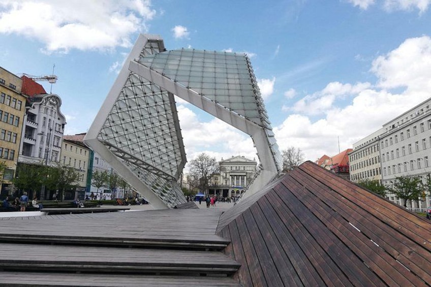 A modern sculpture in an urban setting with buildings in the background. 4