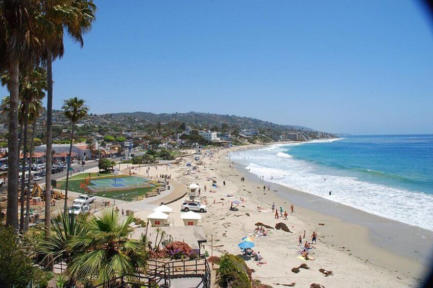 A beach with people, palm trees, and a sports field. 2