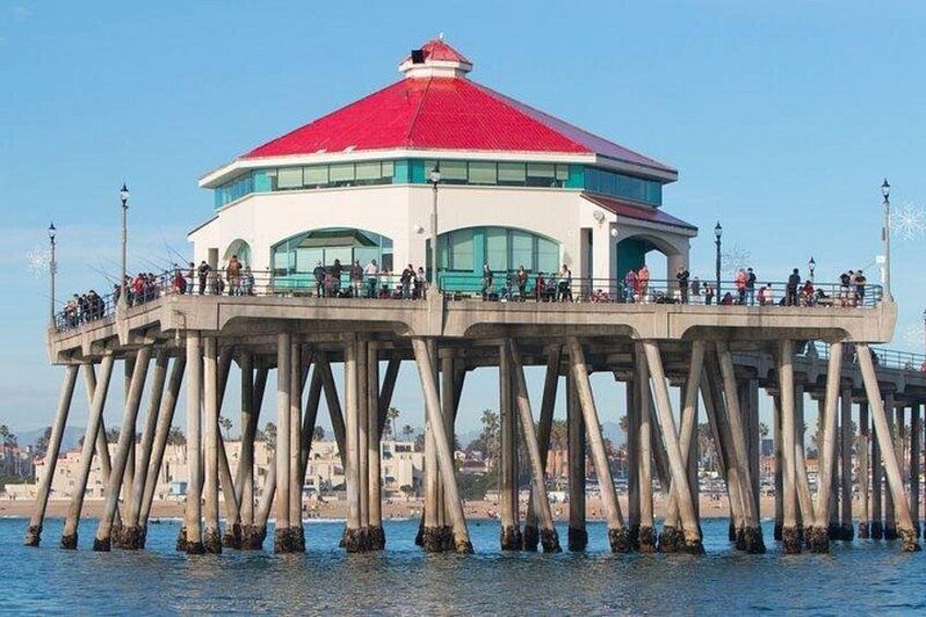 A pier with a red-roofed building, people on the pier, and a coastal cityscape in the background. 1