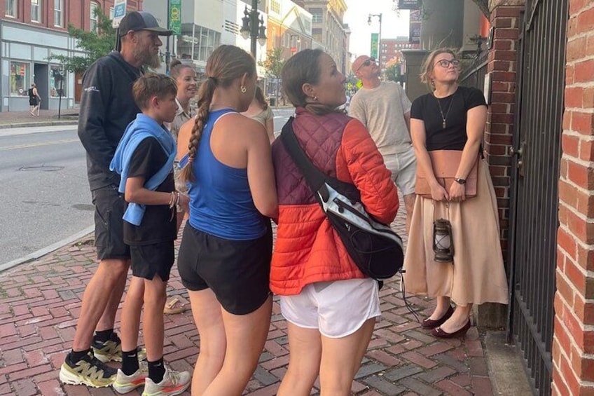 A group of people standing on a brick sidewalk, engaged in conversation. 3