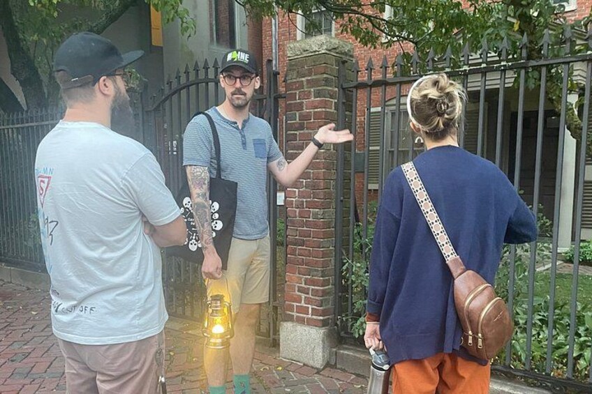 Three people standing on a brick sidewalk, one holding a flashlight. 3