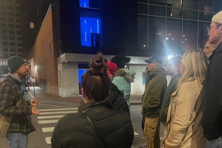 A group of people standing on a street at night. 4