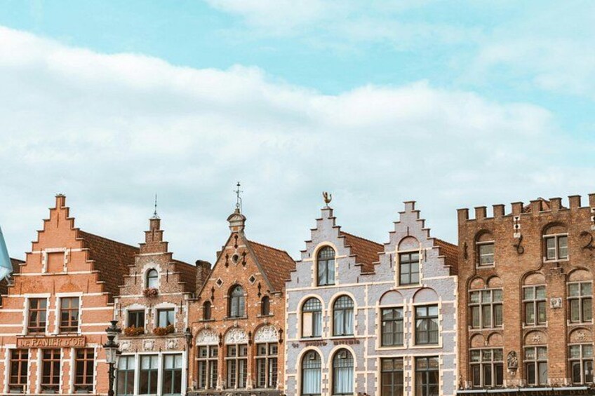 Une rangée de bâtiments historiques présentant différents styles architecturaux, notamment des toits en forme de flèche et des motifs décoratifs en briques. 2