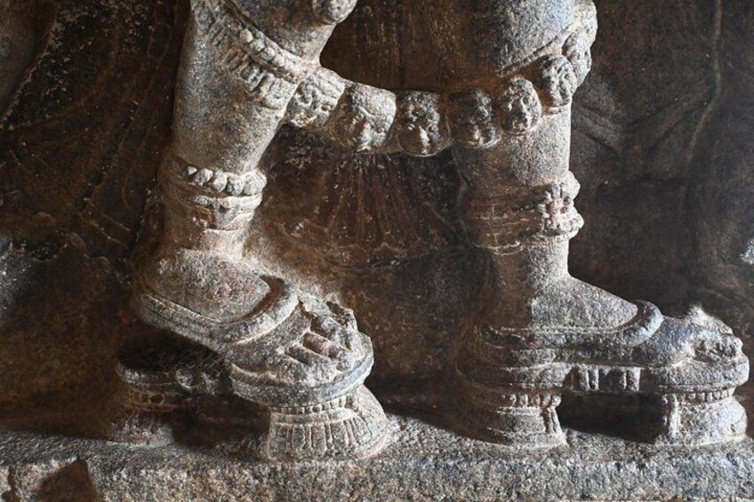 Una escultura de piedra de una figura humana con intrincados detalles en los pies. 3