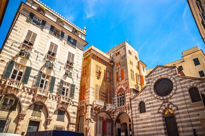 A street with historic buildings, a clock tower, and a clear blue sky. 4