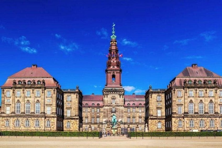 A large historic building with a prominent tower, symmetrical architecture, and a statue in front. 2