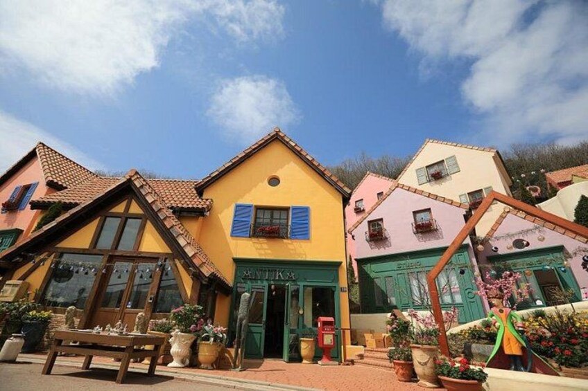 A colorful building with a yellow facade and a green door, surrounded by potted plants and a bench. 4