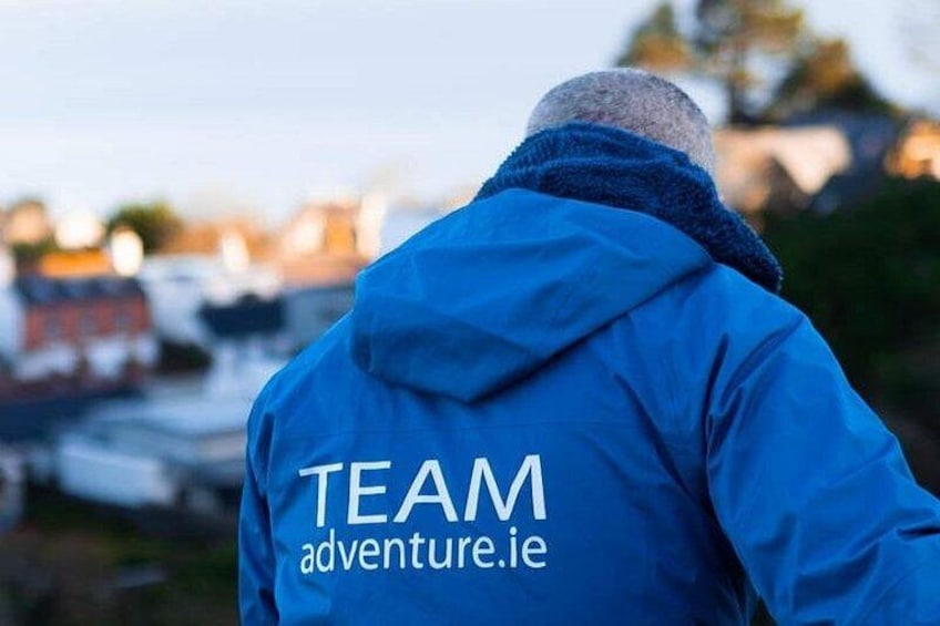 En person iført en blå jakke med 'TEAM adventure.ie' på ryggen. 3