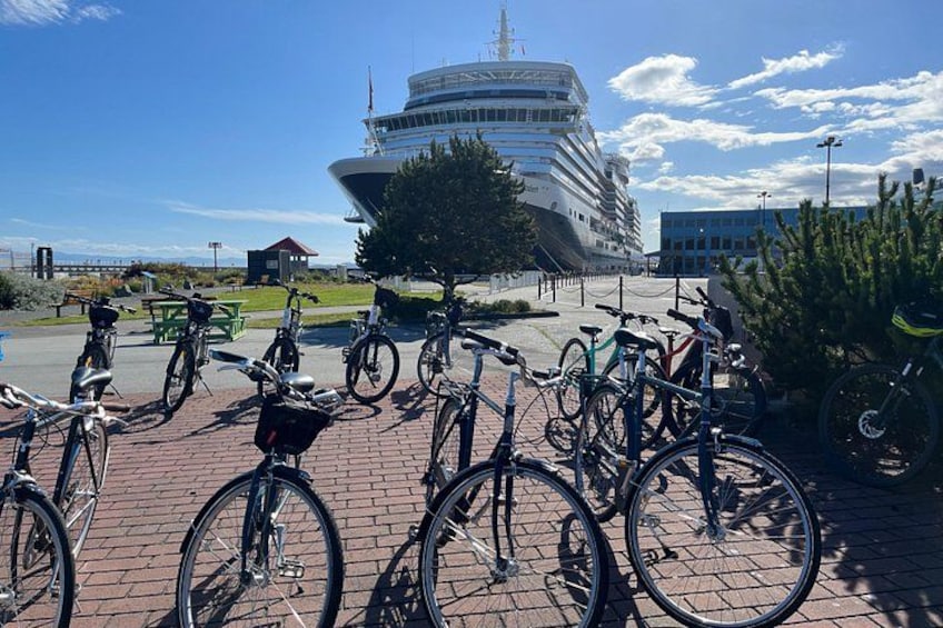 Bicycles parked on a brick pavement, a modern building, and a clear blue sky. 2