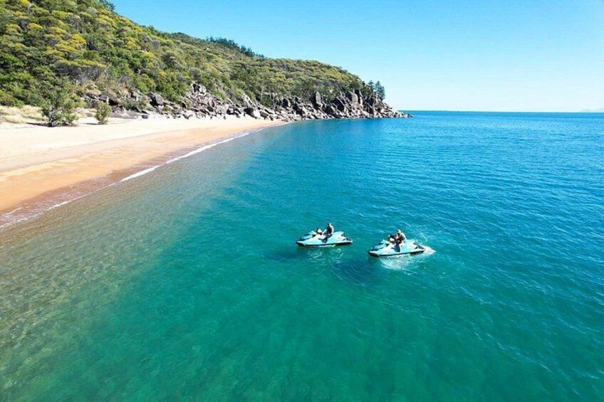 A beach with clear turquoise water, two small boats, and a sandy shore with greenery. 2