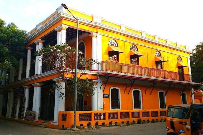 A two-story building with yellow and white exterior walls, large windows, and a balcony. 3