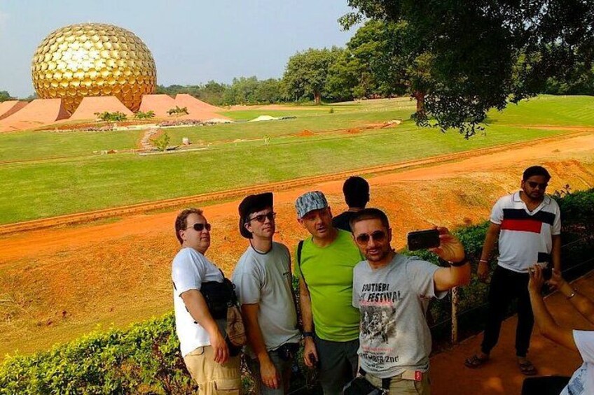 A group of people standing in a field with a large spherical building in the background. 2