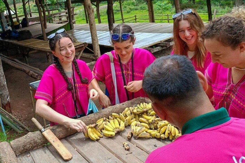 A group of people in pink shirts gathered around a wooden table with bananas. 2