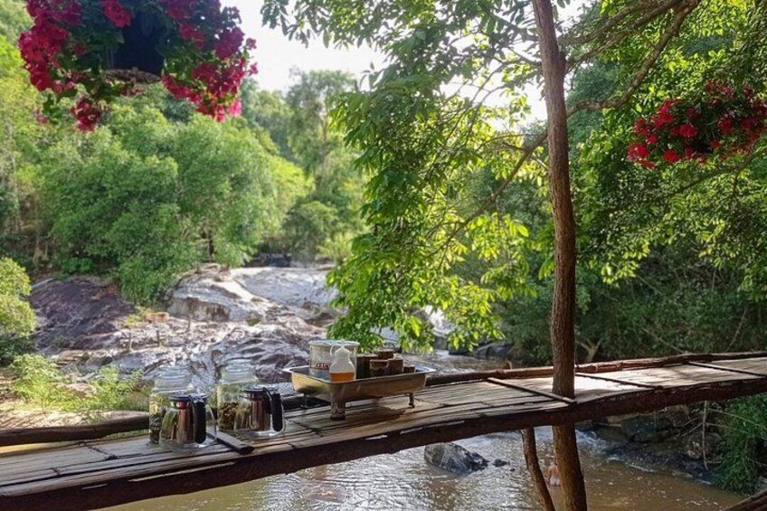 A wooden bridge over a river with a picnic setup on the left. 5